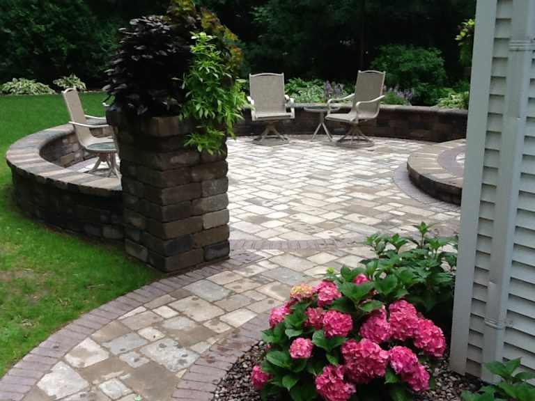 rock tile patio with walkway, sit wall and pillar with chairs and landscaping