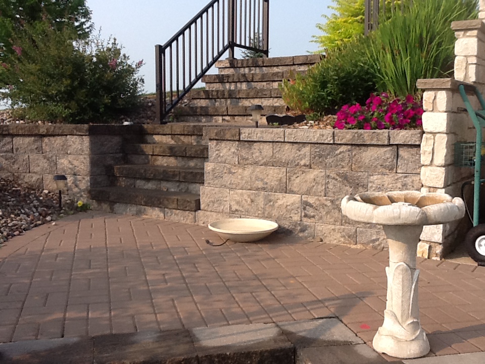 stone stairs and metal railing in brick retaining wall leading to patio