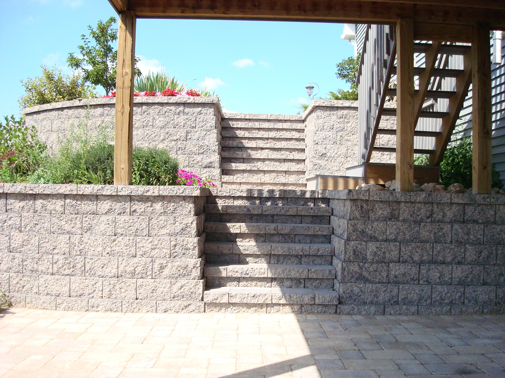 stone steps in two-level brick retaining wall underneath wooden deck