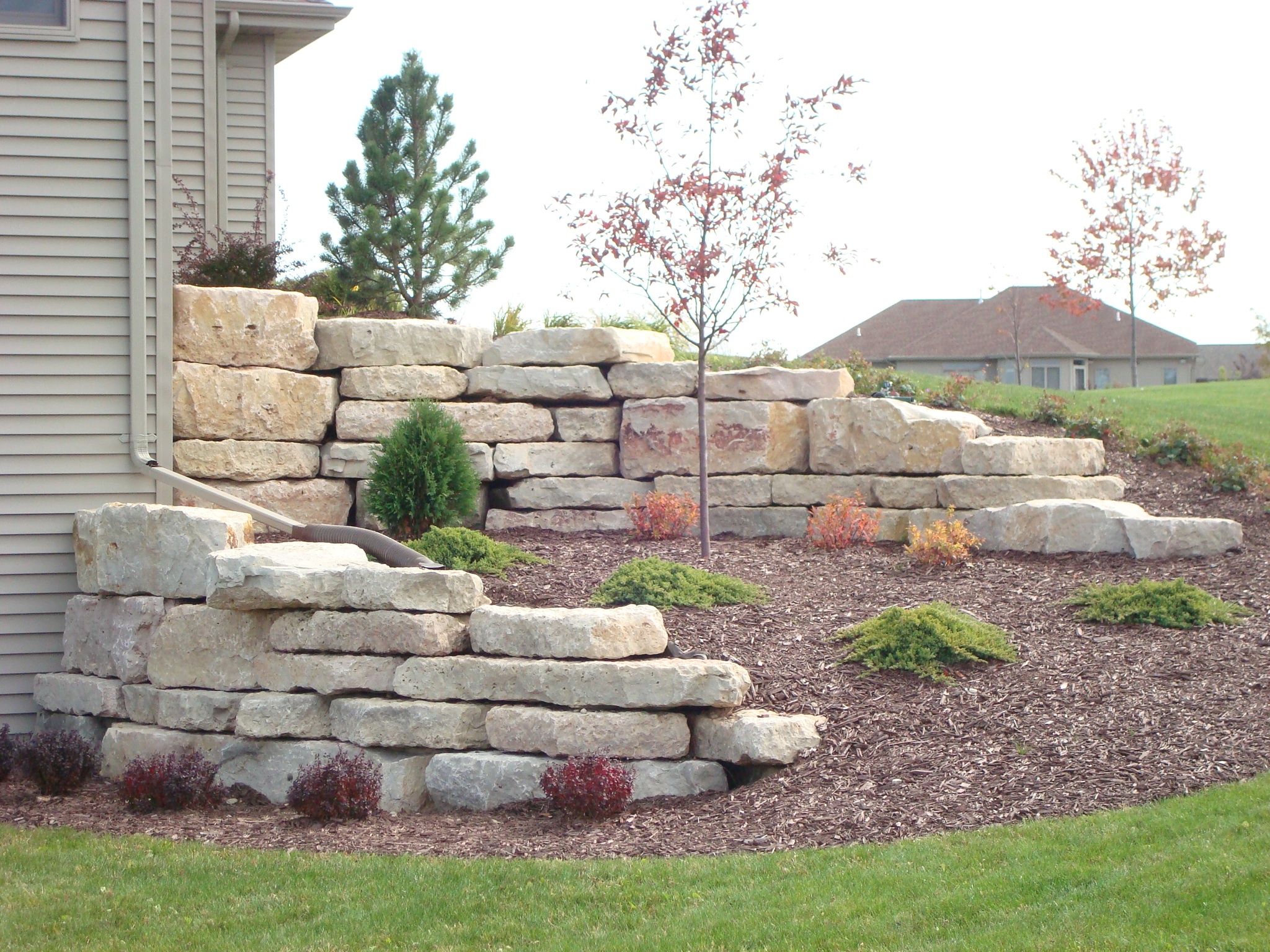 stone retaining walls in landscaping along hill next to house