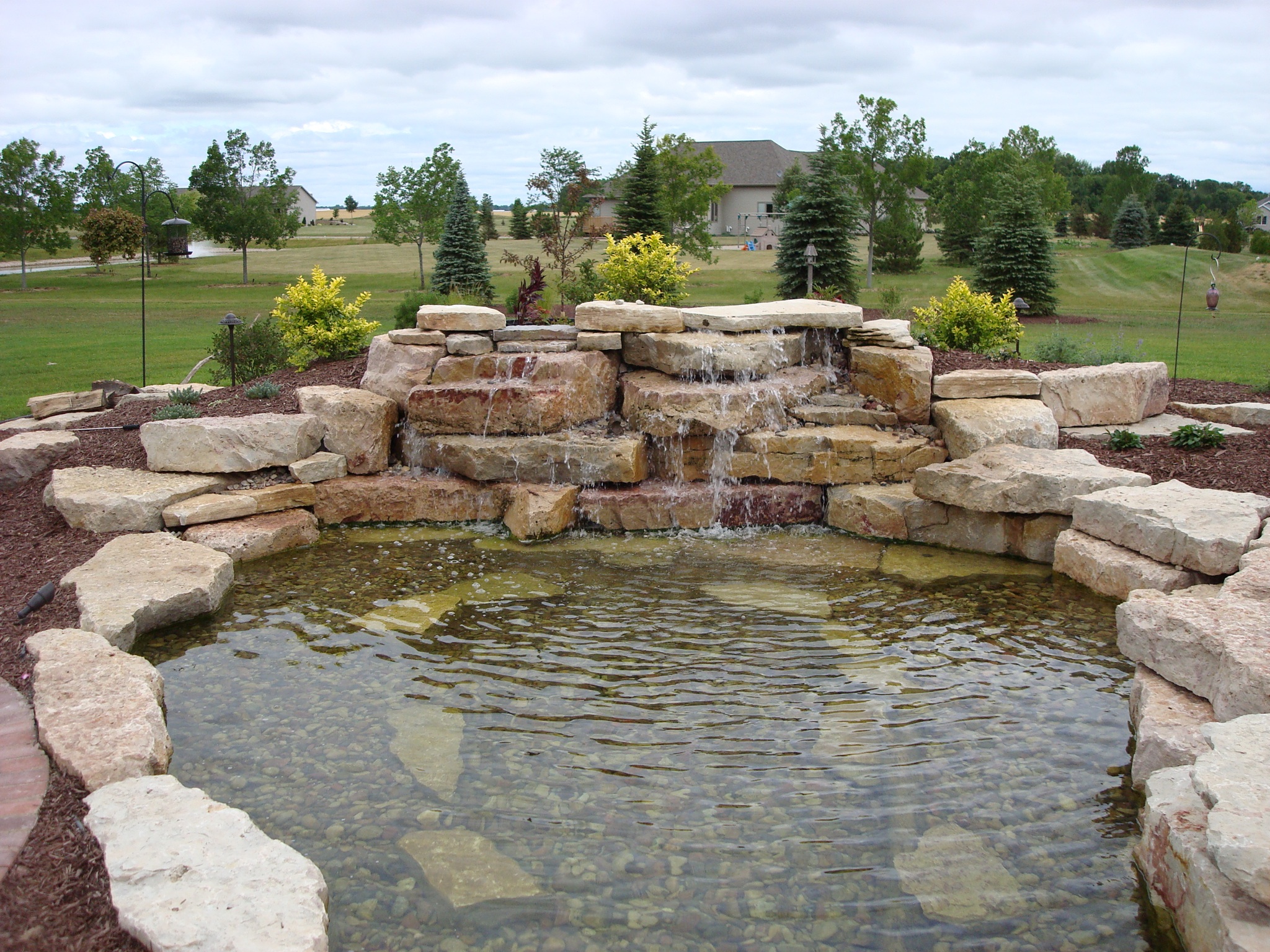pond surrounded by stacked stone with cascading water feature