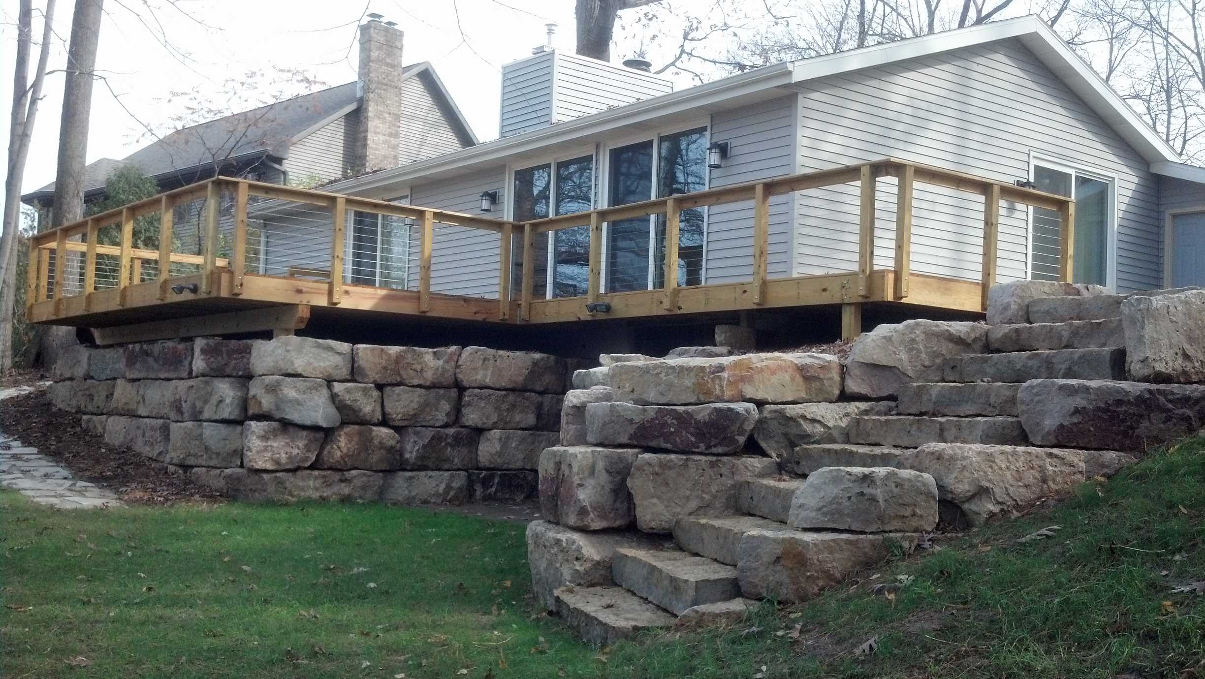 stacked rock retaining walls supporting wooden deck along house
