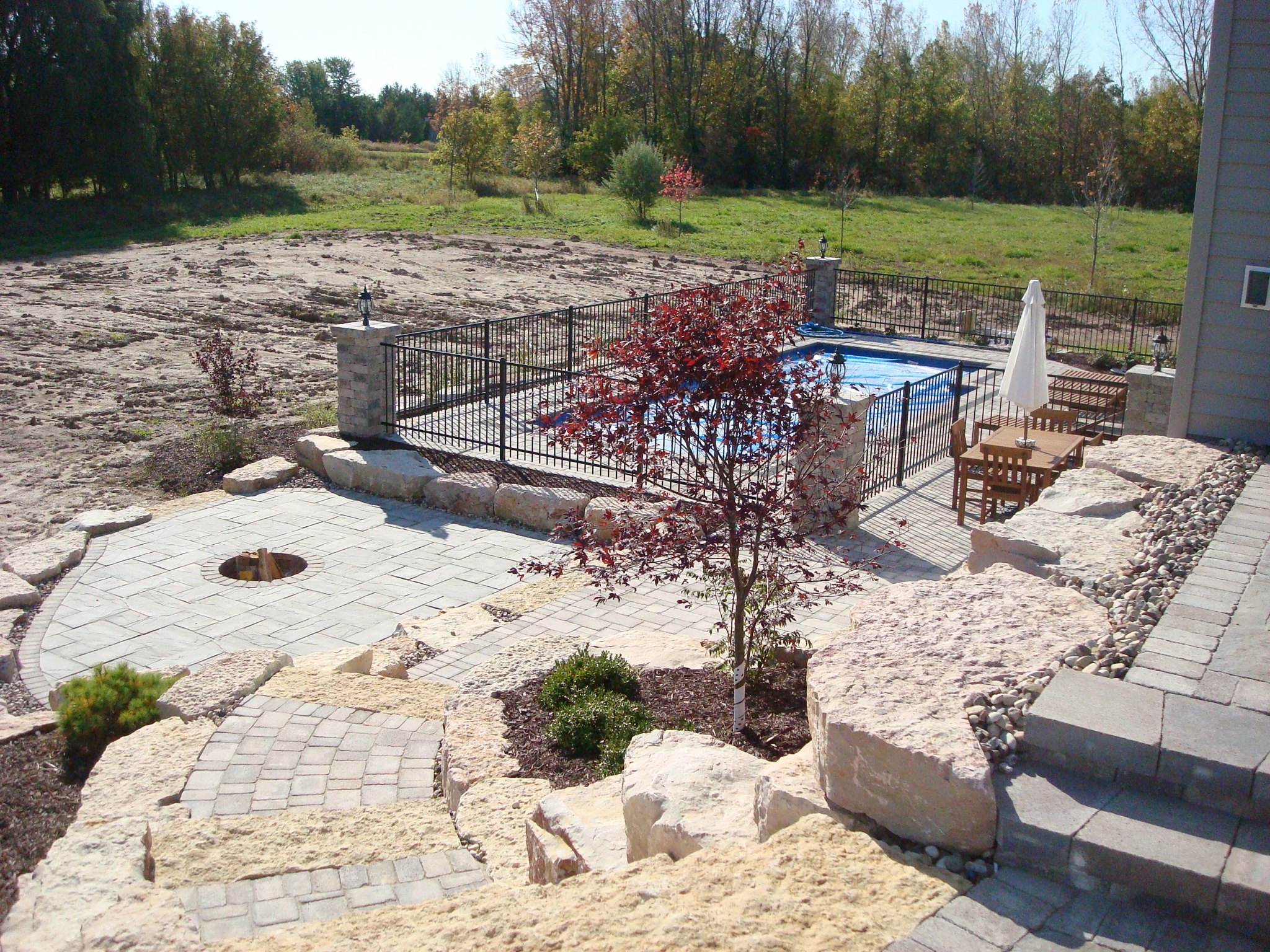 decorative retaining wall stairs leading to small patio and fenced-in pool area