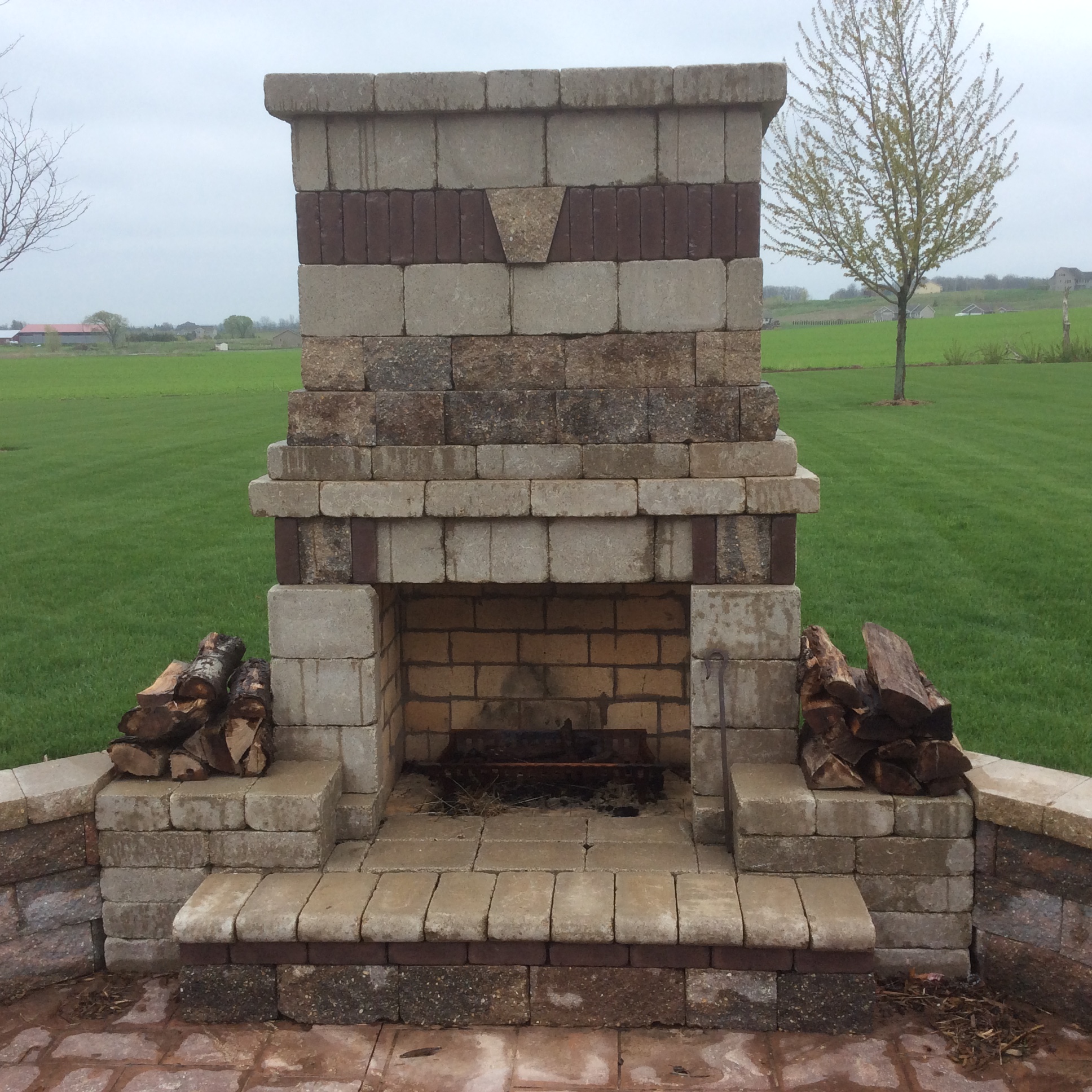large outdoor brick fireplace with wood piled on sides