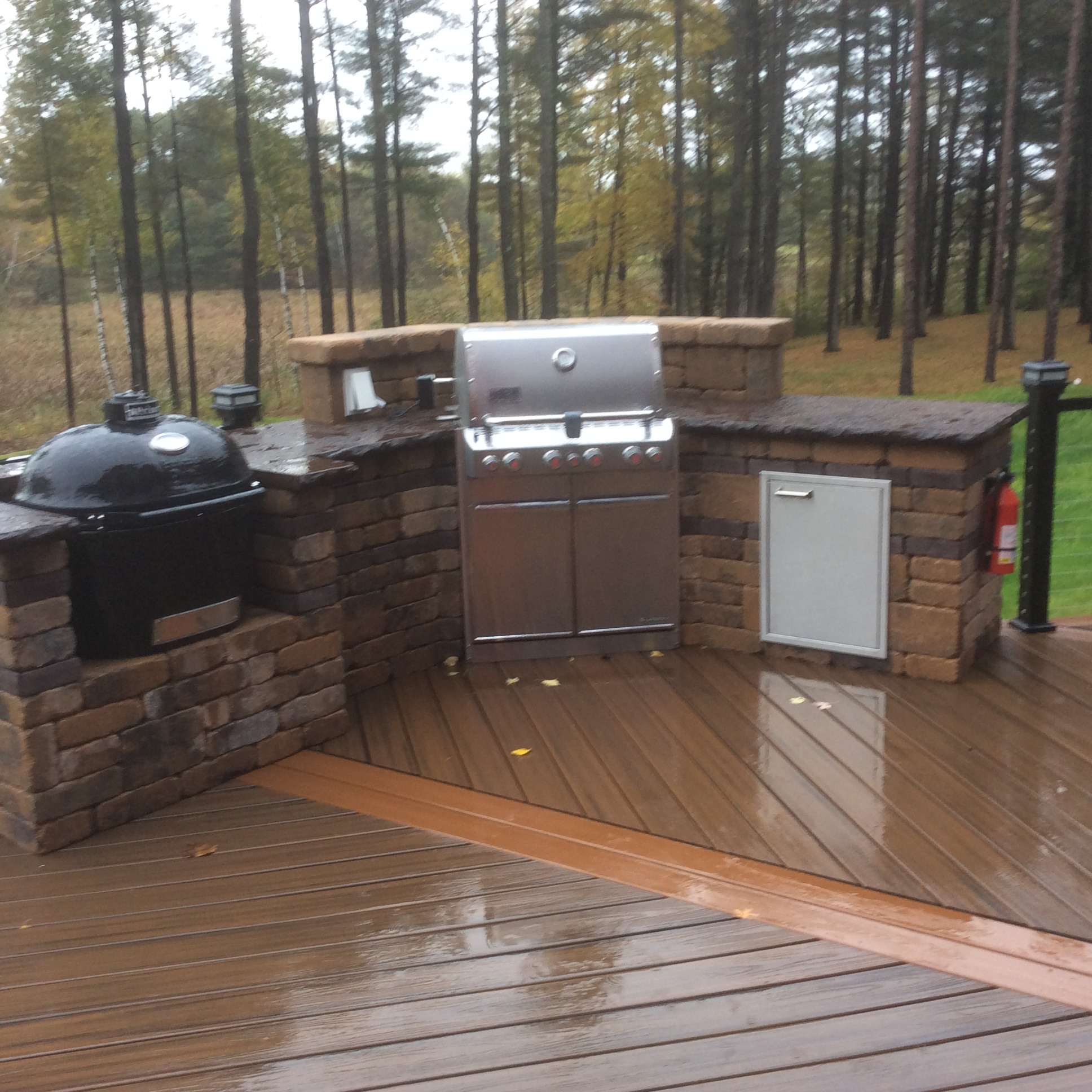 outdoor kitchen with grill and smoker on deck in rain