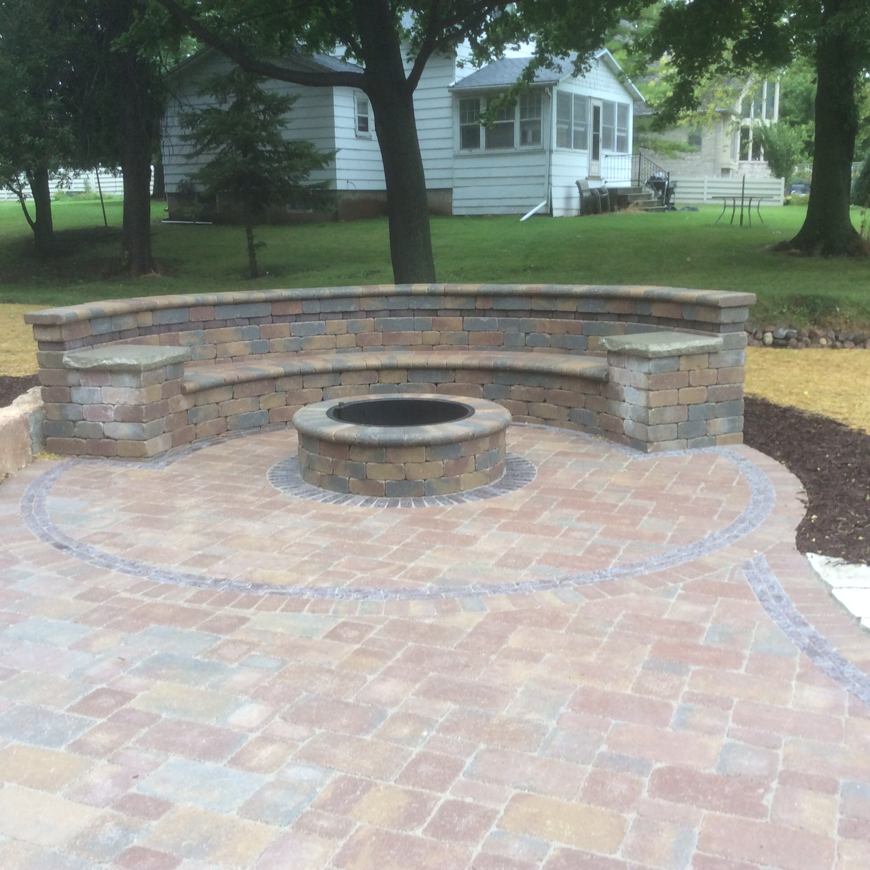 fire pit in half-circle patio with semi-circle stone bench 