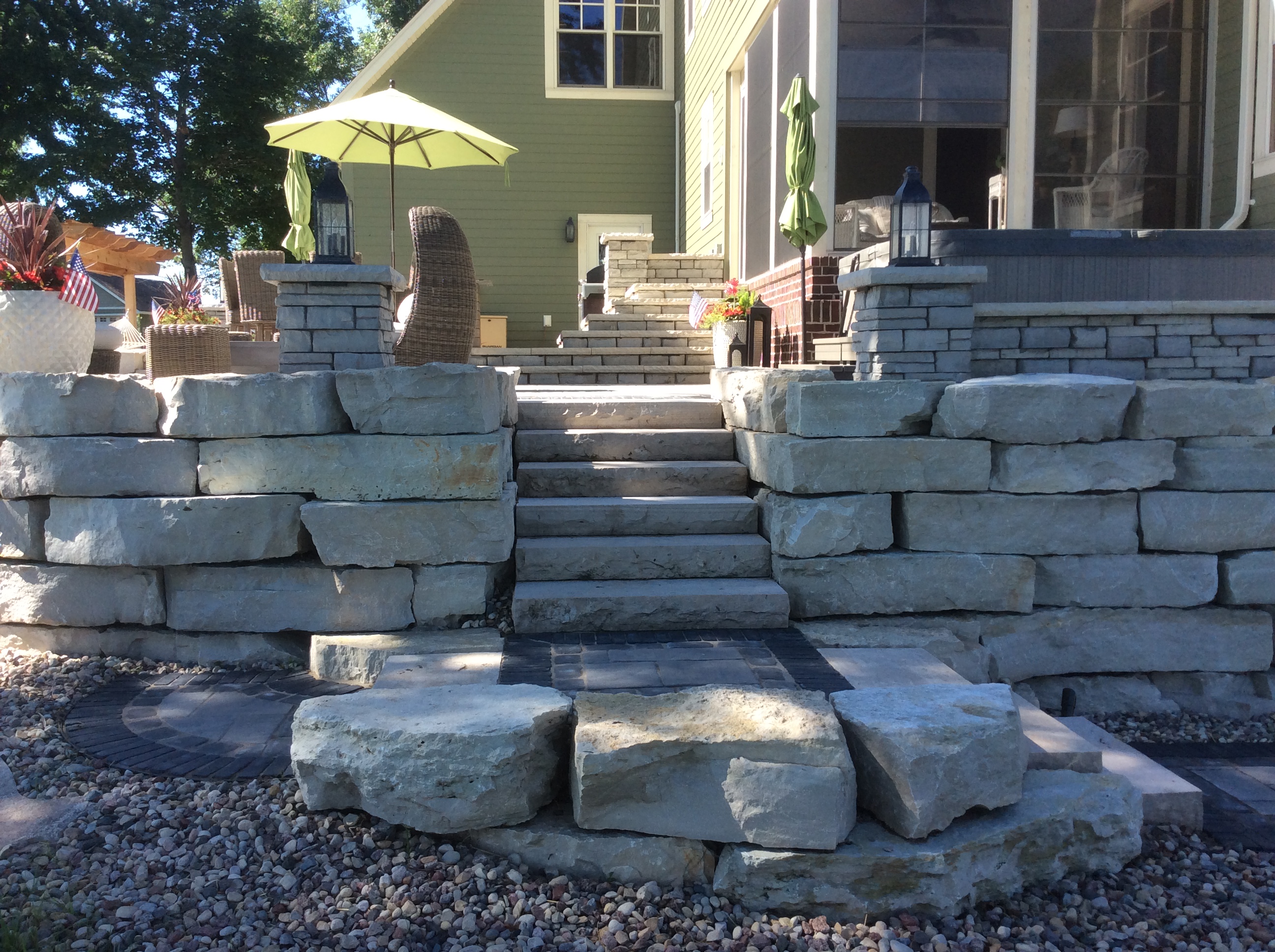 stacked stone retaining wall with stone steps leading to patio seating area